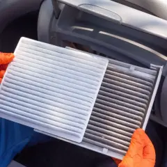 Rękawiczki pomagają w wymianie filtra kabinowego. Nowy, biały filtr obok starego, brudnego.