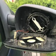 Rozpoczęta wymiana wkładu lusterka. Widoczne mechanizmy regulacji i przewody.