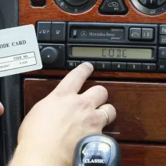Karta z kodem radia Mercedes-Benz i palec wprowadzający kod. Dowiedz się, jak odblokować radio po wpisaniu złego kodu.