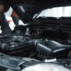 Mechanik pracuje przy silniku, wykonując czyszczenie wtryskiwaczy benzynowych.