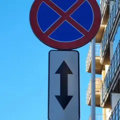 Znak zakaz parkowania ze strzałką w górę i w dół informuje, że postój jest zabroniony po obu stronach drogi.