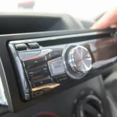 Dłoń wyjmuje radio samochodowe. Może to być pierwszy krok, jak znaleźć kod do radia, jeśli go zapomniałeś.