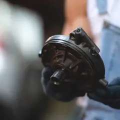 Mechanik w rękawiczkach trzyma element serwa hamulcowego. Objawy awarii mogą być niepokojące.