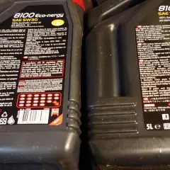 Dwie czarne butelki oleju silnikowego Motul 8100 Eco-nergy SAE 5W30 z etykietami.