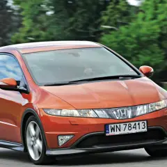 Pomarańczowy Honda Civic 8 tuning na drodze, z zielonymi drzewami w tle.