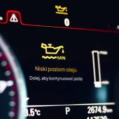 Pomarańczowa kontrolka oleju świeci się na desce rozdzielczej, informując o niskim poziomie oleju. "Niski poziom oleju. Dolej, aby kontynuować jazdę.