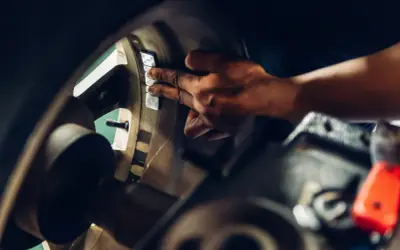 Mechanik przykleja ciężarki do felgi, by wyeliminować drgania kierownicy przy 120 km/h.