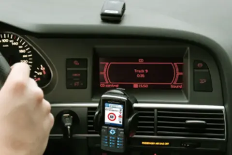 Ręka na kierownicy, telefon z nawigacją i ekran radia w samochodzie. Może to być pomocne, jak odkodować radio.
