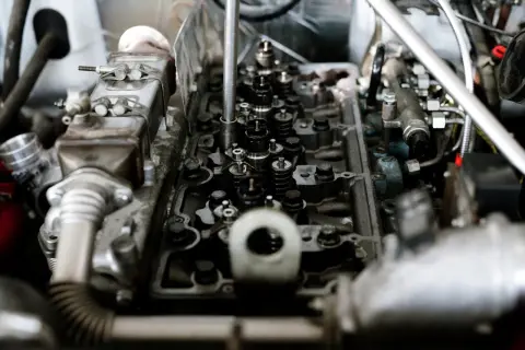 Mechanik diagnozuje stukanie w silniku, badając zawory i wtryskiwacze.
