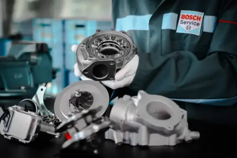 Mechanik w rękawiczkach prezentuje turbosprężarkę, kluczowy element, który daje turbo w samochodzie większą moc i dynamikę.