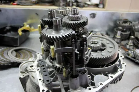 Mechanizm skrzyni biegów z widocznymi kołami zębatymi i łożyskami. Objawy zużycia łożyska skrzyni biegów mogą być różne.
