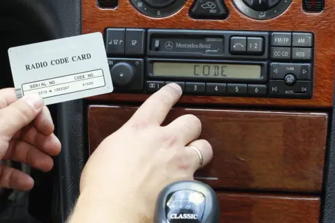 Karta z kodem radia Mercedes-Benz i palec wprowadzający kod. Dowiedz się, jak odblokować radio po wpisaniu złego kodu.