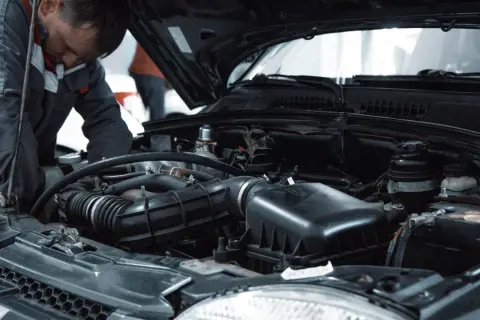 Mechanik pracuje przy silniku, wykonując czyszczenie wtryskiwaczy benzynowych.