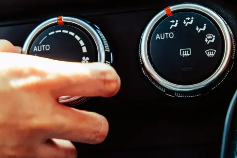 Dłoń kręci pokrętłem klimatyzacji, słychać ciche syczenie z klimatyzacji.