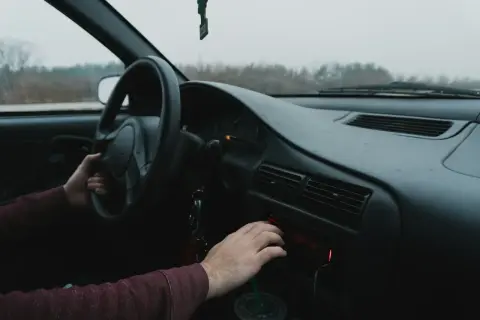 Ręka kierowcy manipuluje radiem samochodowym, szukając wskazówek, jak wyciągnąć radio samochodowe.