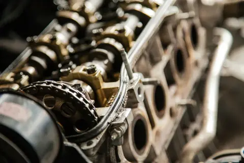 Zbliżenie na mechanizm rozrządu silnika, widoczny łańcuch i koła zębate. Może to być związane z problemem przedmuchów w silniku.