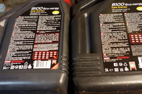 Dwie czarne butelki oleju silnikowego Motul 8100 Eco-nergy SAE 5W30 z etykietami.