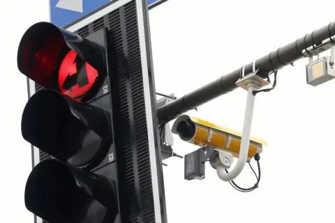 Czerwone światło sygnalizacji świetlnej ze strzałką w lewo i kamerą rejestrującą.