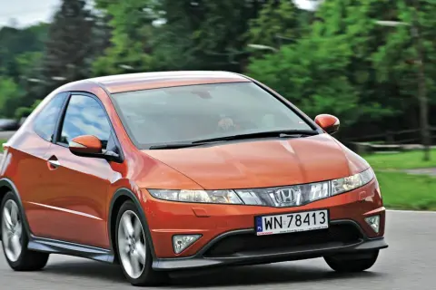Pomarańczowy Honda Civic 8 tuning na drodze, z zielonymi drzewami w tle.