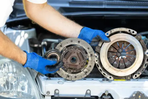 Mechanik pokazuje zużyte części: sprzęgło i dwumasę. Dowiedz się, ile kosztuje wymiana sprzęgła i dwumasy.