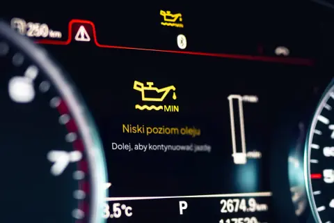 Pomarańczowa kontrolka oleju świeci się na desce rozdzielczej, informując o niskim poziomie oleju. "Niski poziom oleju. Dolej, aby kontynuować jazdę.