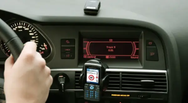 Ręka na kierownicy, telefon z nawigacją i ekran radia w samochodzie. Może to być pomocne, jak odkodować radio.