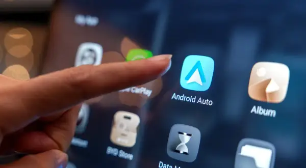 Palec dotyka ikony Android Auto na ekranie, pokazując, jak dodać aplikacje do Android Auto.