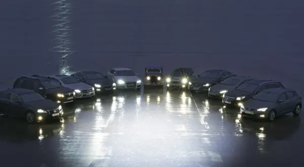 Rząd samochodów z włączonymi światłami, porównanie xenon vs led.