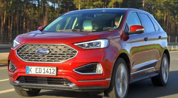 Czerwony Ford Edge na drodze, z widocznym grillem i tablicą rejestracyjną K ED 1412.