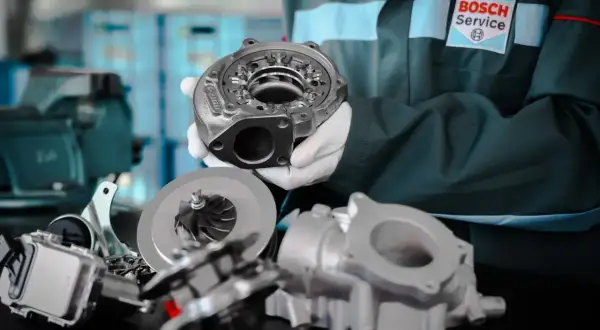 Mechanik w rękawiczkach prezentuje turbosprężarkę, kluczowy element, który daje turbo w samochodzie większą moc i dynamikę.