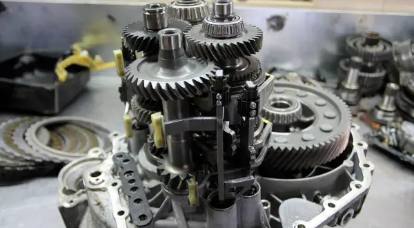 Mechanizm skrzyni biegów z widocznymi kołami zębatymi i łożyskami. Objawy zużycia łożyska skrzyni biegów mogą być różne.