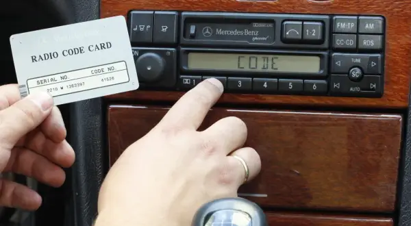 Karta z kodem radia Mercedes-Benz i palec wprowadzający kod. Dowiedz się, jak odblokować radio po wpisaniu złego kodu.