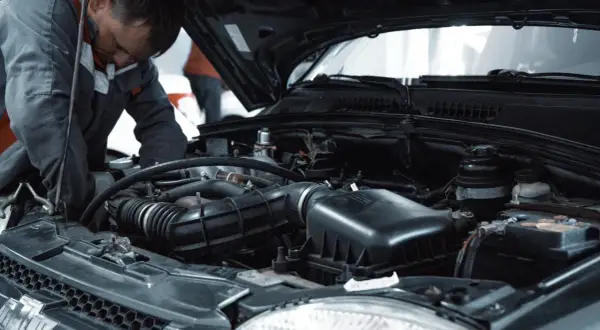Mechanik pracuje przy silniku, wykonując czyszczenie wtryskiwaczy benzynowych.
