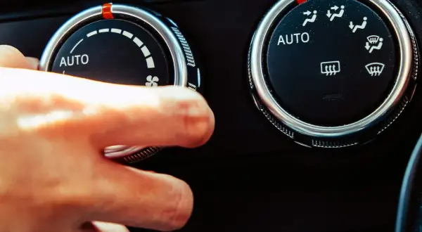 Dłoń kręci pokrętłem klimatyzacji, słychać ciche syczenie z klimatyzacji.