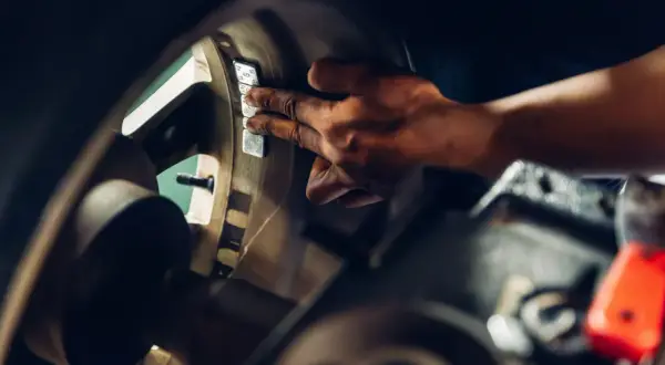 Mechanik przykleja ciężarki do felgi, by wyeliminować drgania kierownicy przy 120 km/h.