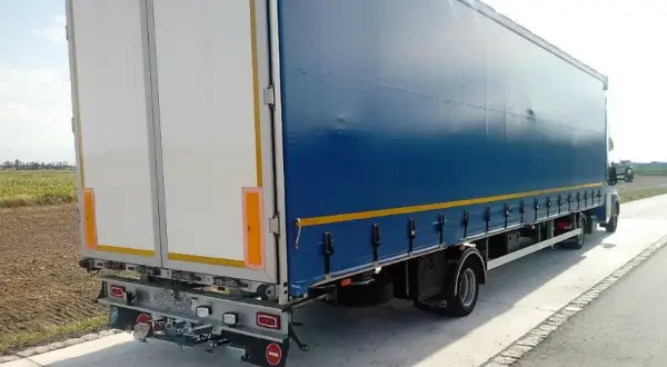 Ciężarówka z niebieską plandeką i białymi drzwiami z tyłu. Zastanawiasz się, ile waży ciągnik siodłowy?