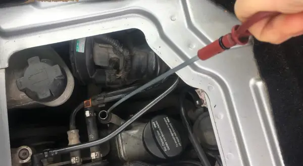 Sprawdzanie poziomu oleju silnikowego: check engine oil level co to znaczy. Dłoń wyciąga miarkę z silnika.