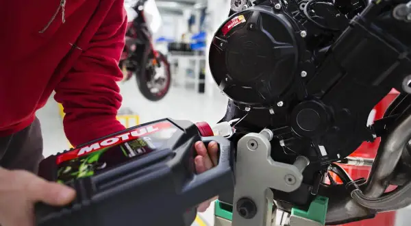 Wymiana oleju w motocyklu 125? Sprawdź, co ile zaleca producent. Mechanik nalewa olej Motul do silnika.