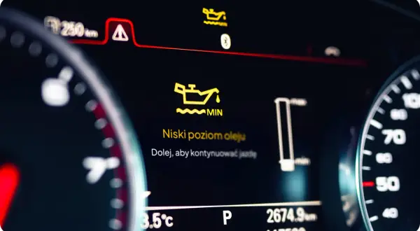 Pomarańczowa kontrolka oleju świeci się na desce rozdzielczej, informując o niskim poziomie oleju. "Niski poziom oleju. Dolej, aby kontynuować jazdę.