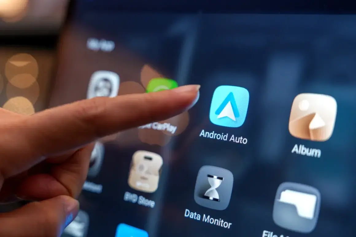 Palec dotyka ikony Android Auto na ekranie, pokazując, jak dodać aplikacje do Android Auto.