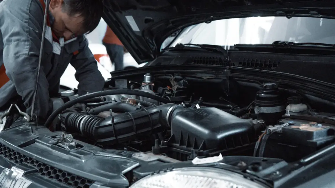 Mechanik pracuje przy silniku, wykonując czyszczenie wtryskiwaczy benzynowych.