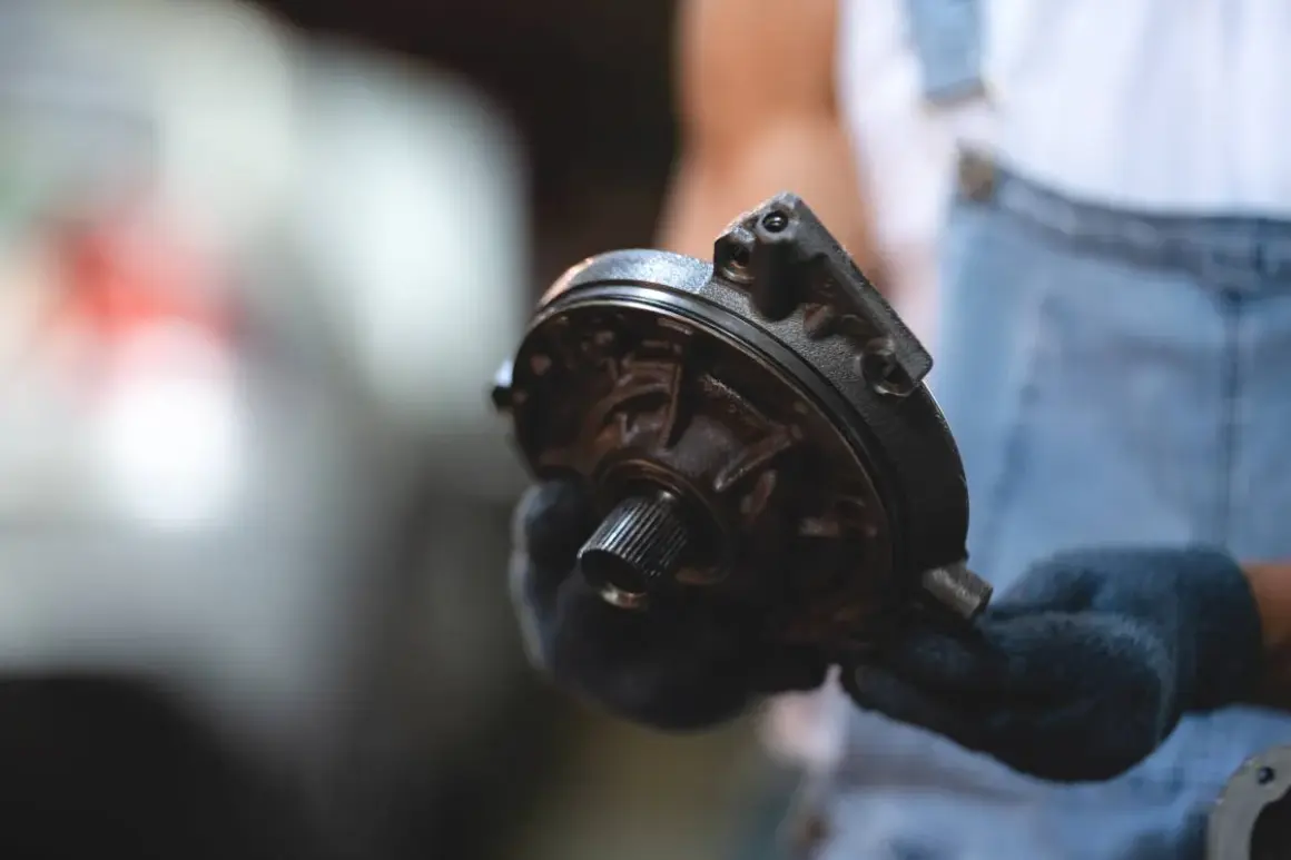 Mechanik w rękawiczkach trzyma element serwa hamulcowego. Objawy awarii mogą być niepokojące.