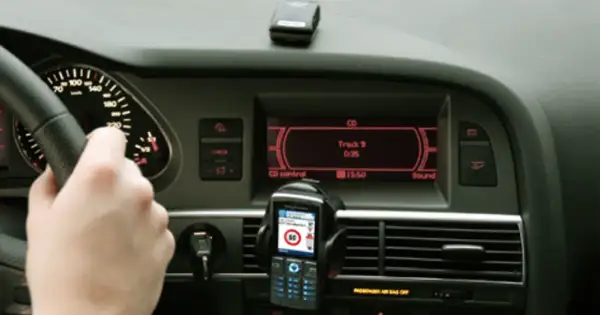 Ręka na kierownicy, telefon z nawigacją i ekran radia w samochodzie. Może to być pomocne, jak odkodować radio.