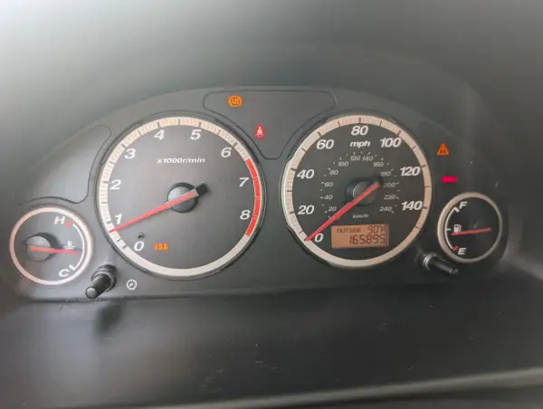 Kontrolki na desce rozdzielczej Hondy CR-V: świeci się kontrolka VSA, ABS, hamulców. Temperatura zewnętrzna 90°F, przebieg 165895.