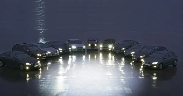 Rząd samochodów z włączonymi światłami, porównanie xenon vs led.