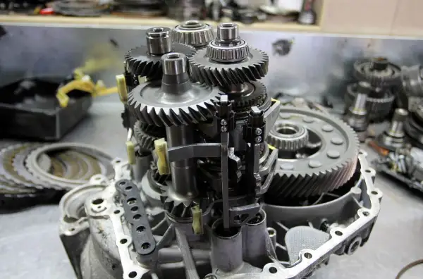 Mechanizm skrzyni biegów z widocznymi kołami zębatymi i łożyskami. Objawy zużycia łożyska skrzyni biegów mogą być różne.