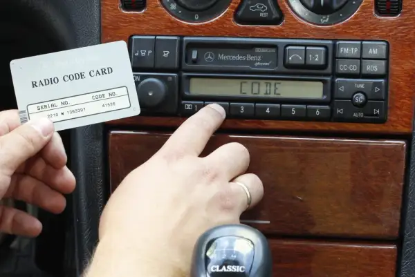Karta z kodem radia Mercedes-Benz i palec wprowadzający kod. Dowiedz się, jak odblokować radio po wpisaniu złego kodu.