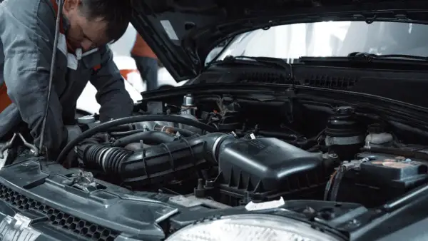 Mechanik pracuje przy silniku, wykonując czyszczenie wtryskiwaczy benzynowych.