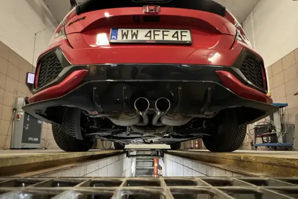 Czerwone auto na podnośniku, podwójny wydech. Zastanawiasz się, ile kosztuje przegląd auta 2026?