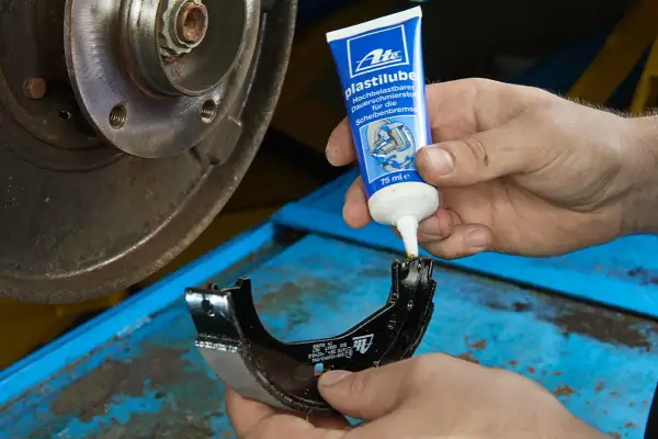 Mechanik aplikuje smar ATE Plastilube na prowadnice szczęk hamulcowych, by zapewnić płynne działanie układu.